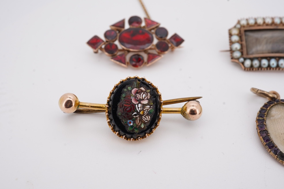 Three assorted Victorian brooches including a 9ct and garnet cluster by Murrle Bennett & Co, 27mm, a micro mosaic bar brooch and a yellow metal and split pearl mourning brooch, together with a gem set oval pendant. Condi